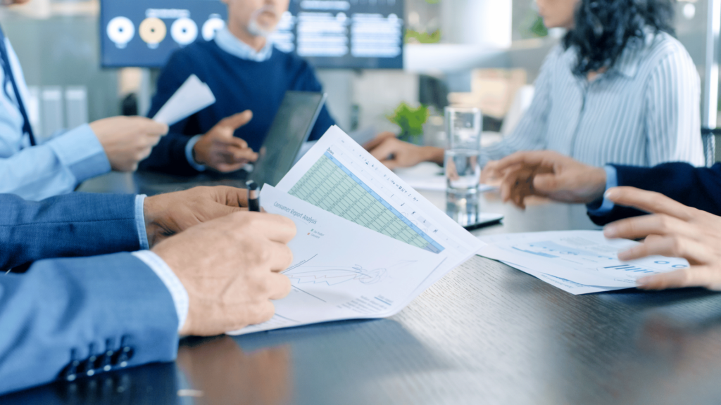 Spotkanie zespołu analizującego raporty i wykresy, co symbolizuje profesjonalne doradztwo i przygotowanie dokumentacji inwestycyjnej.