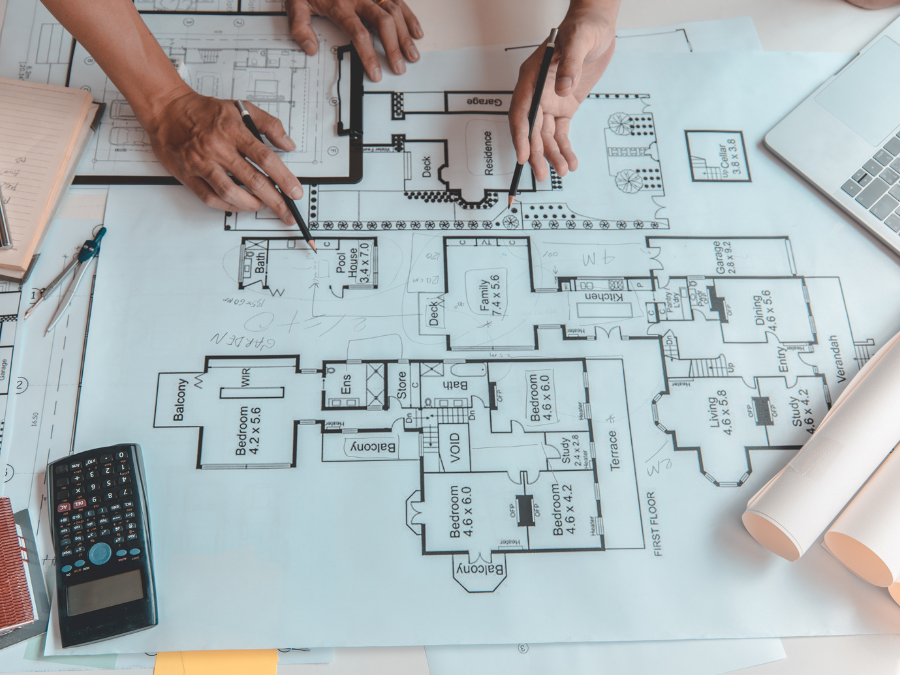 Plan architektoniczny omawiany przez dwóch specjalistów, co symbolizuje etap projektowania hal i planowania inwestycji budowlanych.